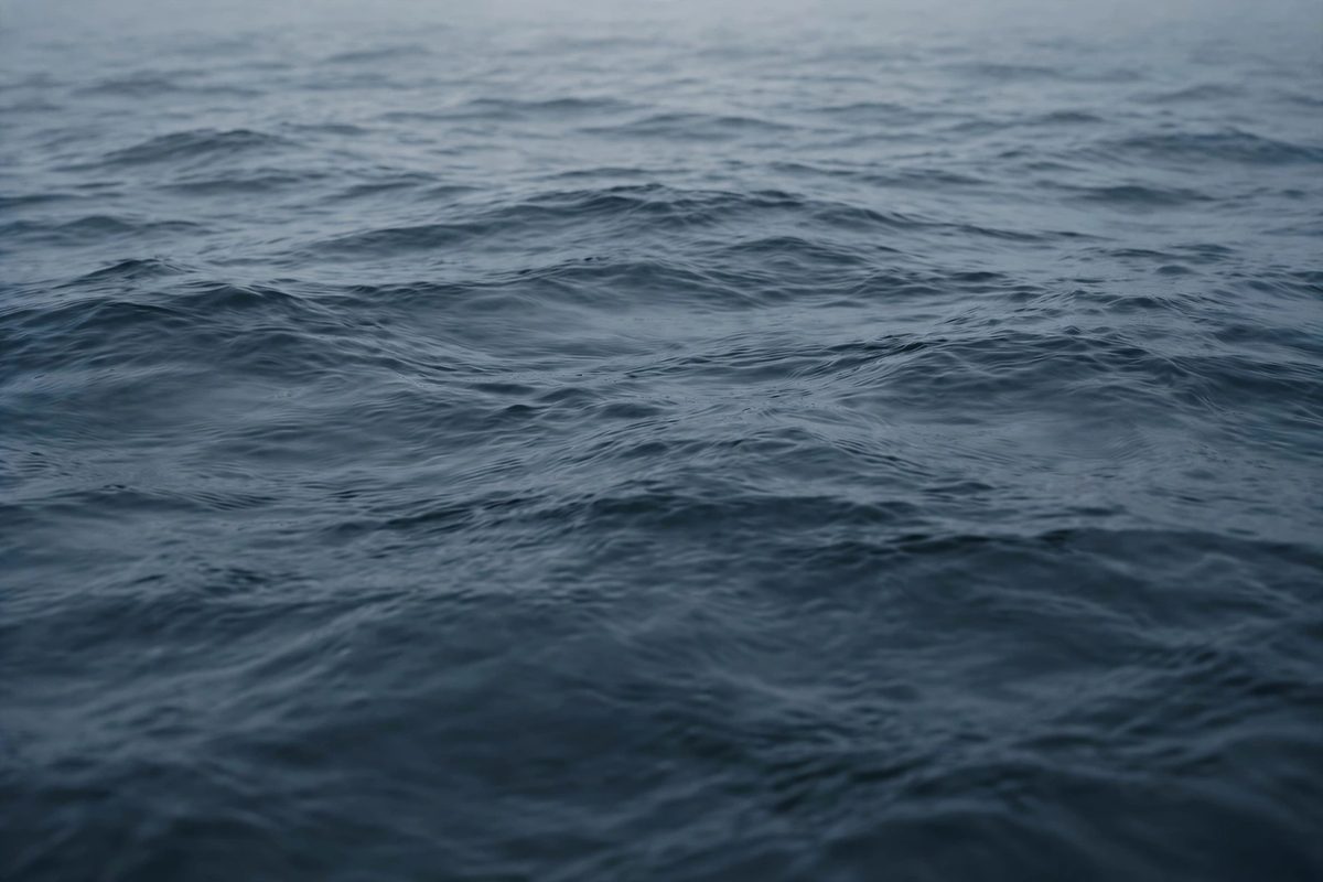 Deep blue-grey water surface with soft ripples in diffused light